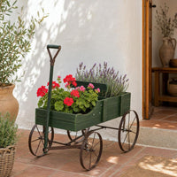 Carrito macetero de madera con geranios junto a una puerta