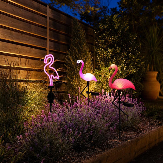 Flamencos solares encendidos en un parterre al anochecer